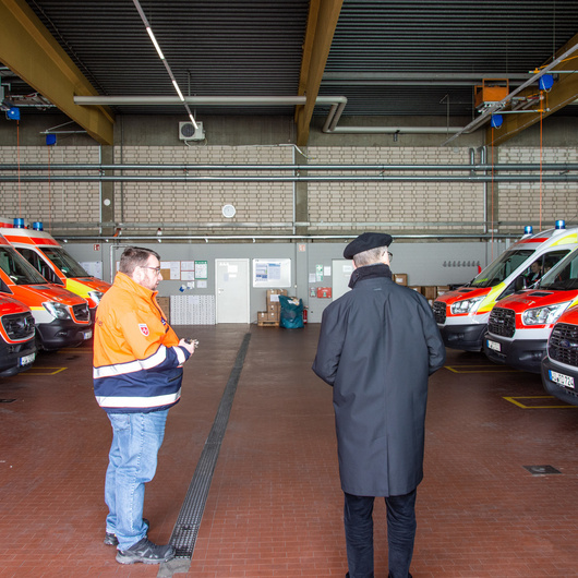 Rettungsdienstleiter Manfred Kirst erläutert Bischof Franz Jung die Funktion der Gerätehalle der Malteser in der Würzburger Mainaustraße.