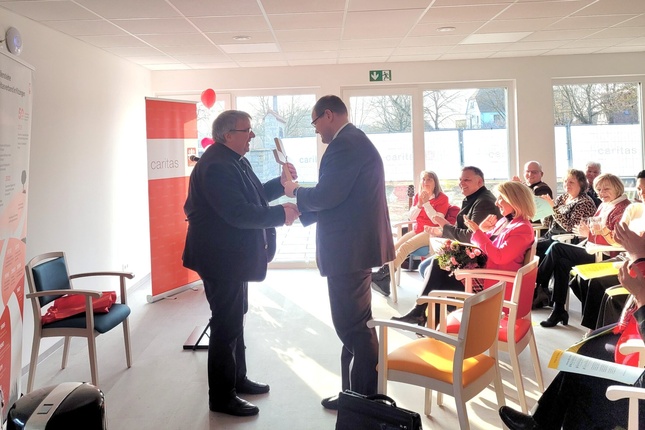 Ein Kreuz für die Tagespflege übergibt Domkapitular Clemens Bieber an Pfarrer Matthias Eller.