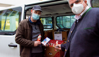 Der Vorsitzende des Diözesan-Caritasverbands, Clemens Bieber (r.), und Hausmeister Alfred Krafft neben am Caritashaus die Schokoladenspende der Edeka Frischemärkte Trabold entgegen.