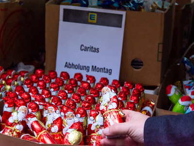 Der Vorsitzende des Diözesan-Caritasverbands, Clemens Bieber (r.), und Hausmeister Alfred Krafft neben am Caritashaus die Schokoladenspende der Edeka Frischemärkte Trabold entgegen.