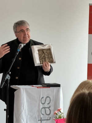 Domkapitular Clemens Bieber überreicht der Tagespflege in Volkach ein Bronzebild.
